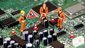 Miniature construction workers repairing electronic components on a green circuit board HD wallpaper