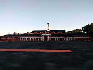 Indian Military Academy Barracks at Dusk with Central Clock Tower and Red Carpet HD wallpaper