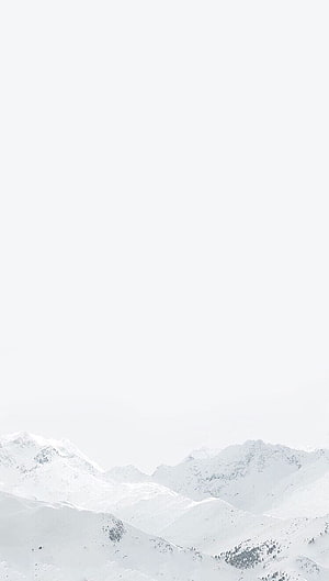 Serene Snow-Covered Mountain Range Under a Pale Winter Sky HD phone wallpaper