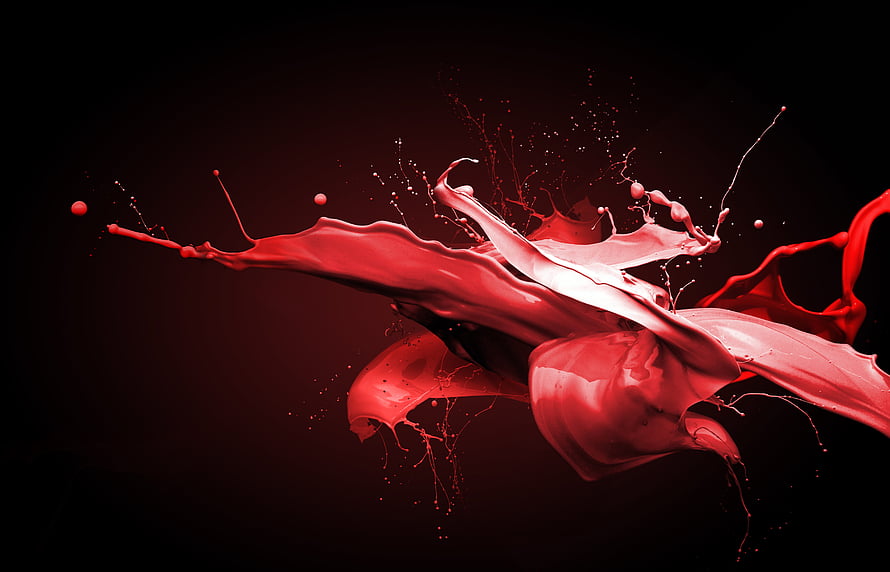 Dynamic red liquid splash frozen in motion against a dark background HD wallpaper
