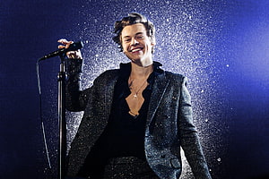 Harry Styles performing on stage in a sparkling suit with confetti and blue lighting HD wallpaper