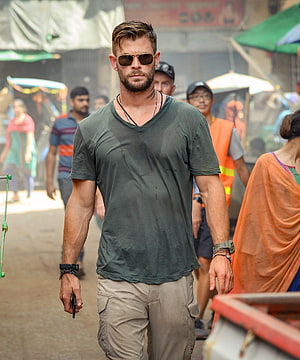 Chris Hemsworth in Extraction Walking Through a Crowded Street Market HD phone wallpaper