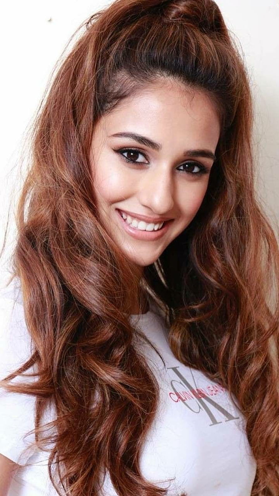 Disha Patani smiling portrait with long wavy auburn hair and white t-shirt HD phone wallpaper