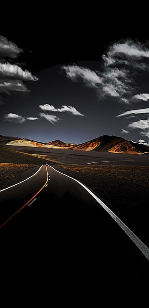 Dramatic Highway Stretching Through Dark Mountain Landscape Under Stormy Sky HD phone wallpaper