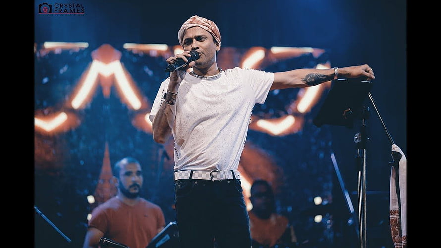 Zubeen Garg performing live on stage with microphone and turban HD wallpaper