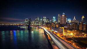 New York City Skyline at Night with Brooklyn Bridge and Long Exposure Traffic Trails HD wallpaper