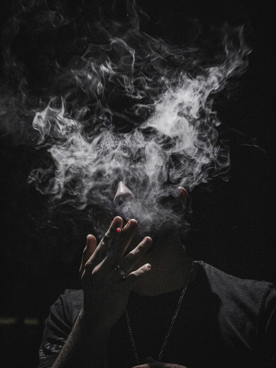 Moody Portrait of a Young Man Exhaling Thick Smoke Against a Dark Background HD phone wallpaper