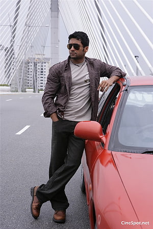 Surya Leaning Against Red Car on Bridge in Ayan Movie Still HD phone wallpaper