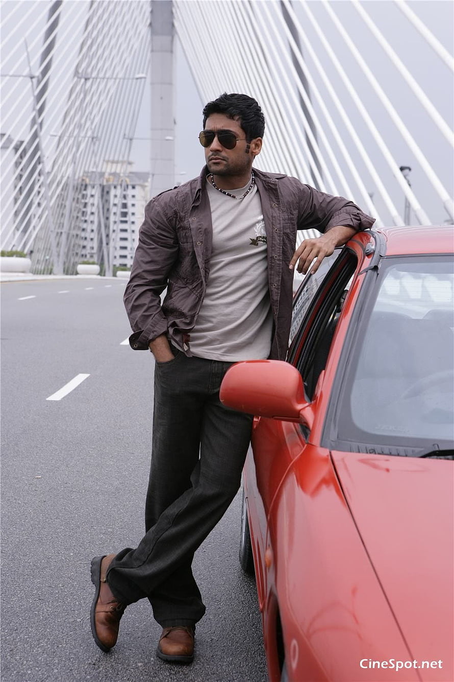 Surya Leaning Against Red Car on Bridge in Ayan Movie Still HD phone wallpaper