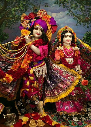 Radha Rani and Krishna in ornate traditional attire with floral garlands and peacock feather headdress HD phone wallpaper