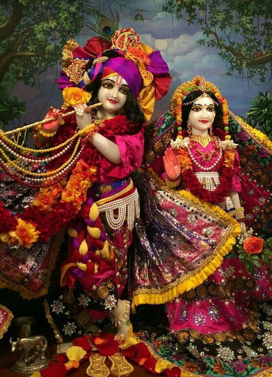 Radha Rani and Krishna in ornate traditional attire with floral garlands and peacock feather headdress HD phone wallpaper