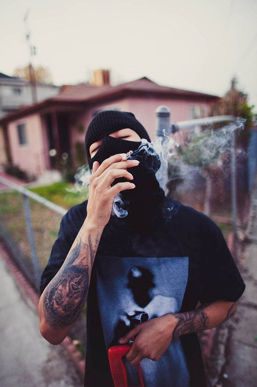 Man in black ski mask smoking cigarette with visible arm tattoos in residential neighborhood HD phone wallpaper