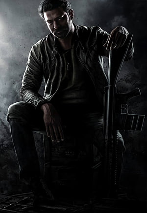 Prabhas as Salaar in a gritty action pose with a rifle against a dark smoky backdrop HD phone wallpaper