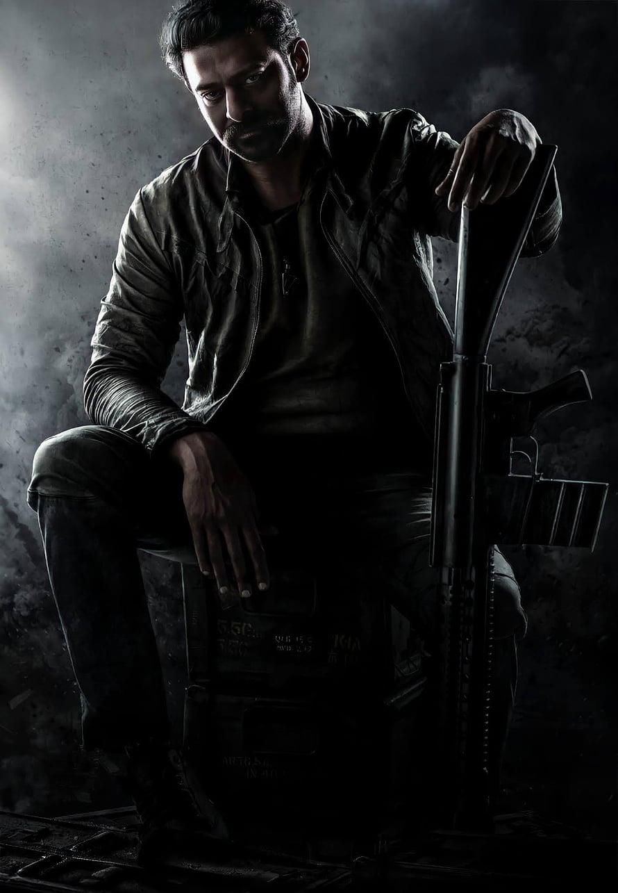 Prabhas as Salaar in a gritty action pose with a rifle against a dark smoky backdrop HD phone wallpaper
