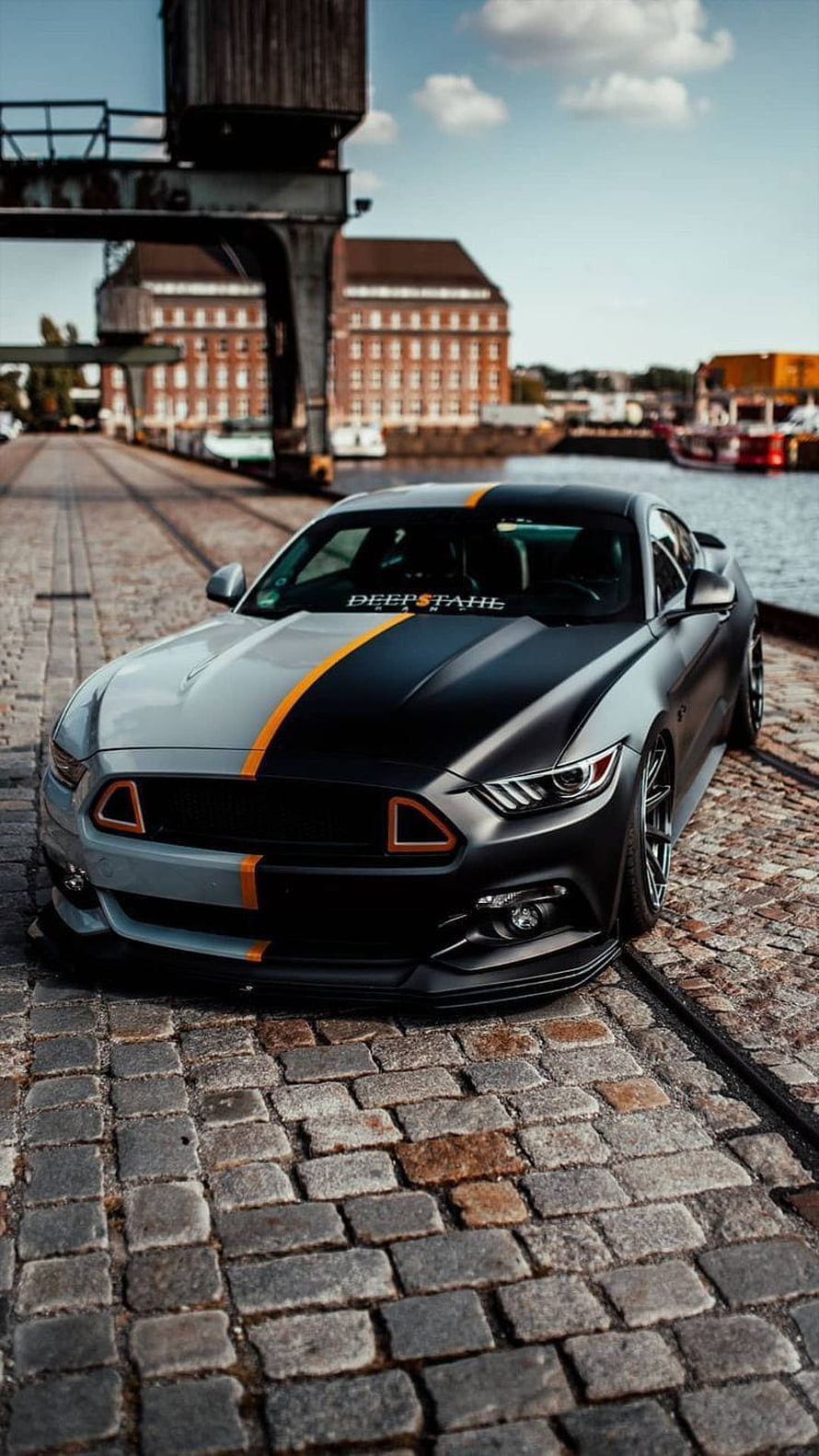 Matte Black Ford Mustang GT with Orange Racing Stripes Parked on Cobblestone Dock HD phone wallpaper