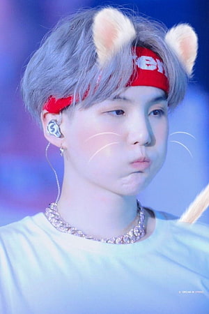 Suga of BTS in a playful cat costume with red headband and whiskers on stage HD phone wallpaper