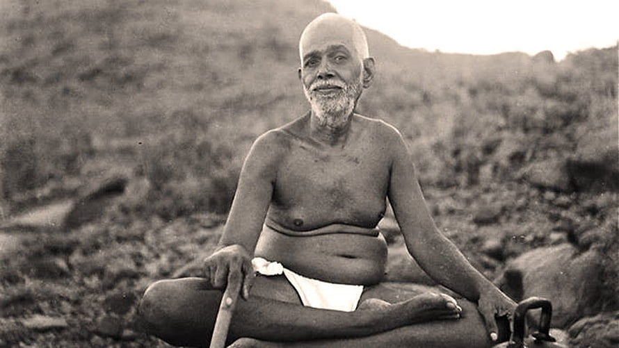 Sri Ramana Maharshi seated in meditation on a rocky hillside in a vintage black and white photograph HD wallpaper