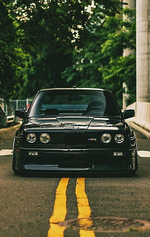 Black BMW E30 M3 Coupe Front View Parked on Urban Street with Yellow Road Markings HD phone wallpaper