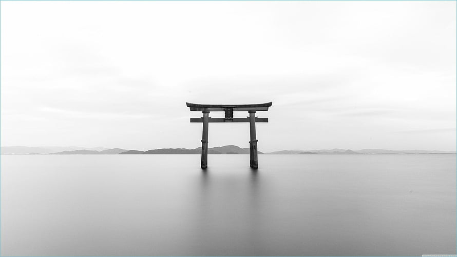Minimalist Black and White Torii Gate Standing in Calm Water with Distant Mountains HD wallpaper