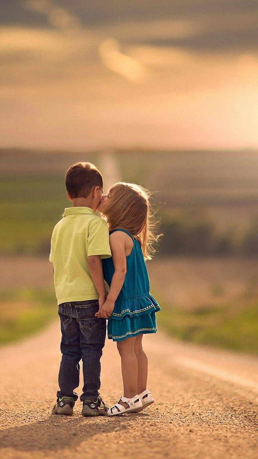 Two young children standing on a country road at golden hour with a soft warm sunset glow HD phone wallpaper