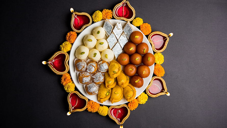 Traditional Indian Mithai Sweets Arranged on a Plate with Diya Lamps and Marigold Flowers for Diwali HD wallpaper