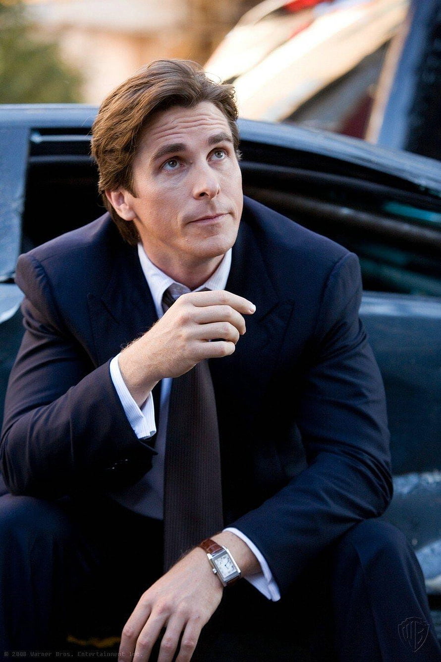 Christian Bale as Bruce Wayne in a dark suit leaning against a car HD phone wallpaper