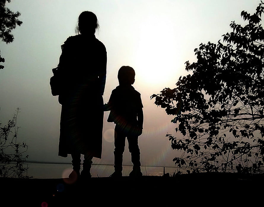 Silhouette of a mother and child standing together at sunset with trees in the background HD wallpaper