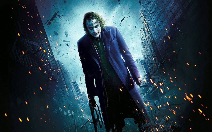 The Joker from The Dark Knight standing in a destroyed city street with flying debris and embers HD wallpaper