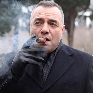 Oktay Kaynarca as Suleyman Cakir smoking a cigar in a dark coat and black gloves HD phone wallpaper