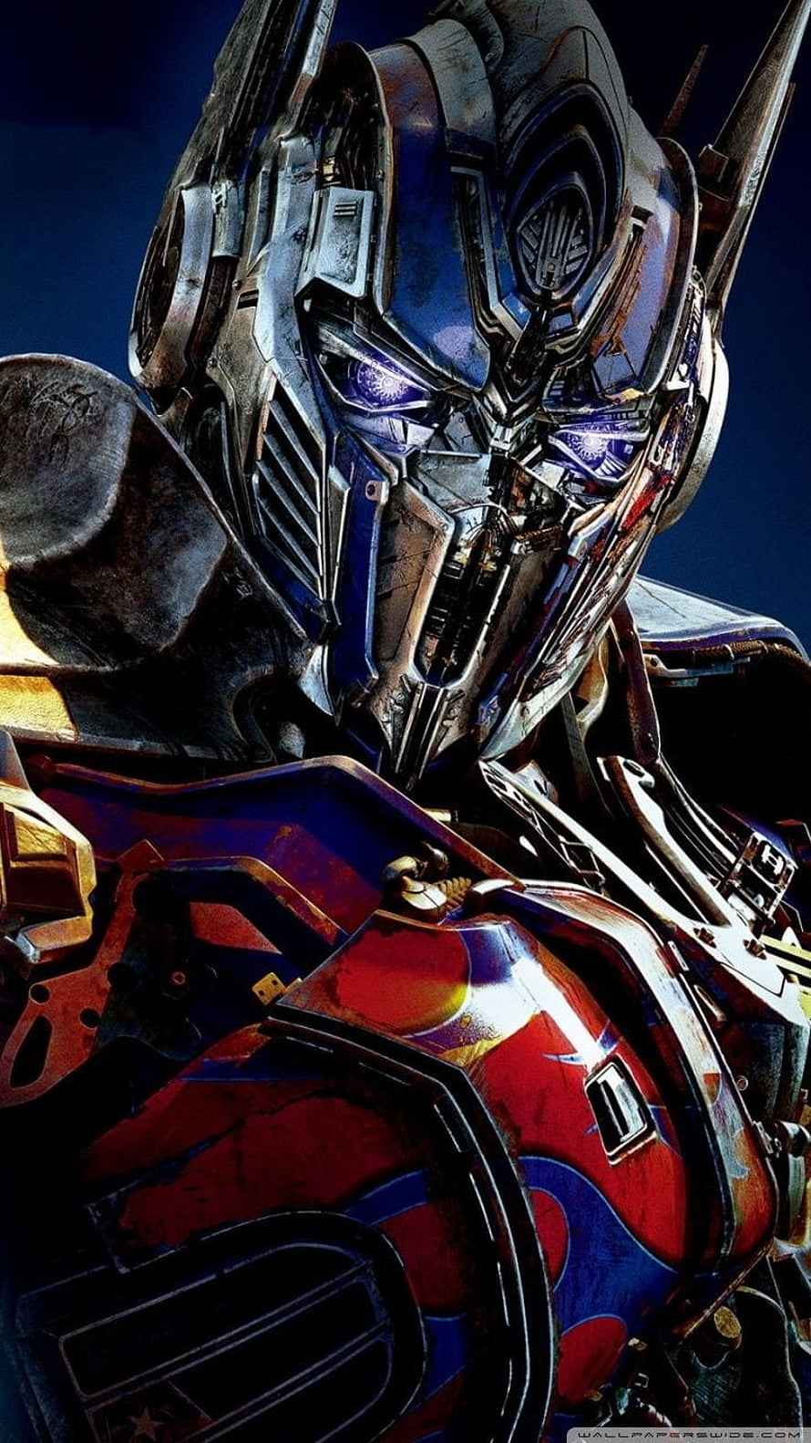 Transformers Optimus Prime Close-Up Portrait with Glowing Blue Eyes and Weathered Armor HD phone wallpaper