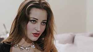 Dani Daniels in a black top with a statement necklace and red lipstick in a soft-lit indoor setting HD wallpaper