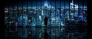 Silhouette of a man standing before a panoramic night cityscape viewed through floor-to-ceiling windows HD wallpaper