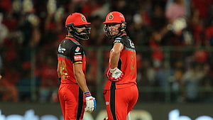 Virat Kohli and AB de Villiers in red cricket gear on the field HD wallpaper