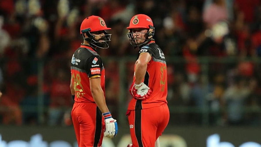 Virat Kohli and AB de Villiers in red cricket gear on the field HD wallpaper
