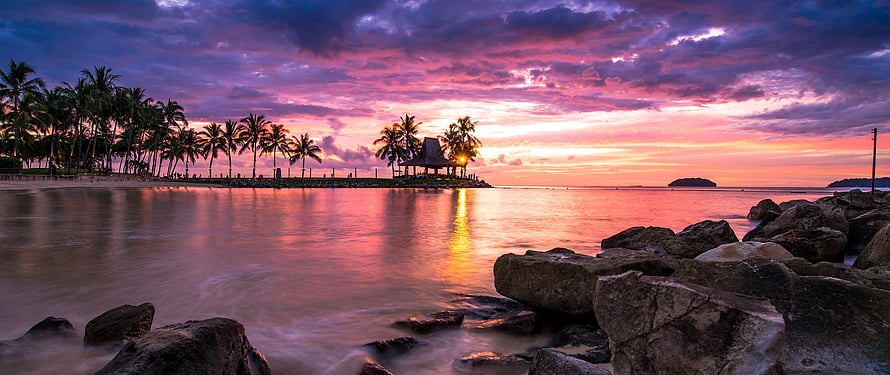 Tropical Beach Sunset with Palm Trees and Rocky Shoreline HD wallpaper