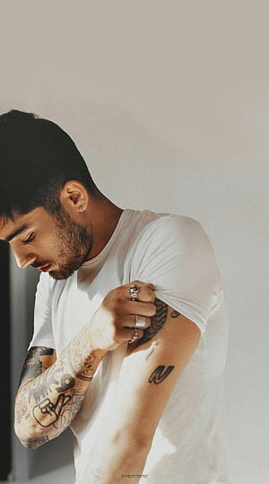 Zayn Malik in a white t-shirt with visible arm tattoos and rings HD phone wallpaper