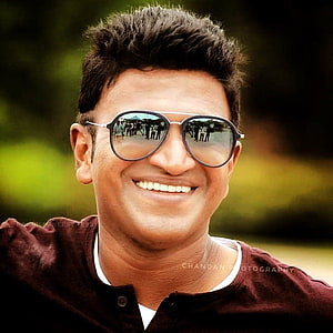 Puneeth Rajkumar smiling portrait wearing aviator sunglasses outdoors HD phone wallpaper