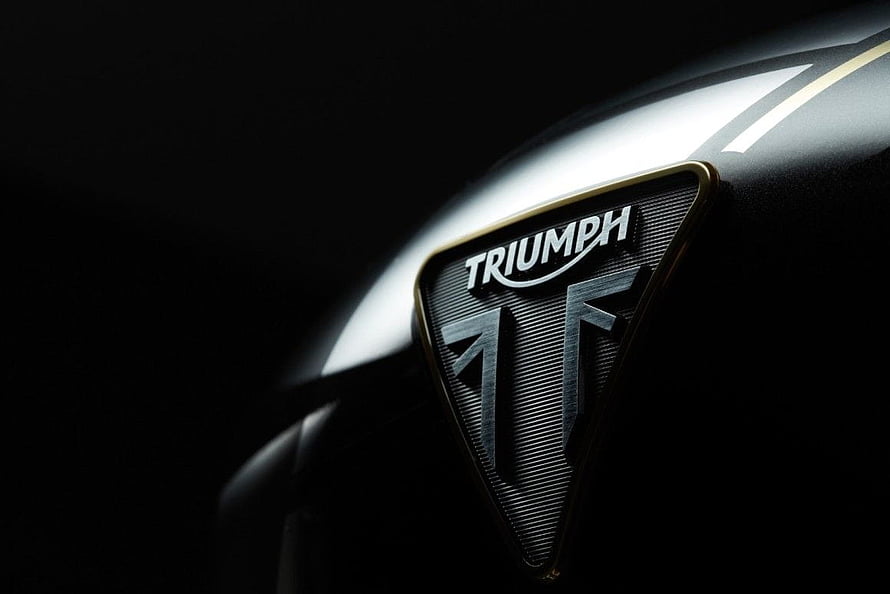 Triumph Motorcycle Emblem Close-Up on Glossy Black Tank with Dramatic Studio Lighting HD wallpaper