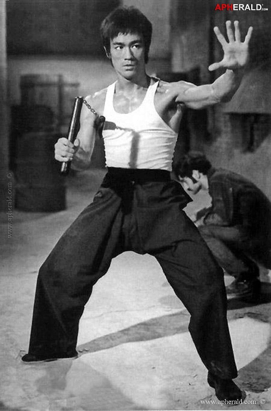 Bruce Lee in a Dynamic Nunchaku Fighting Stance Wearing a White Tank Top HD phone wallpaper