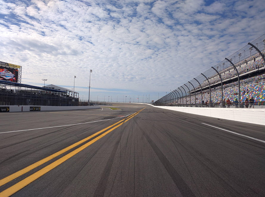Empty NASCAR Race Track With Grandstands And Scattered Clouds Under A Blue Sky HD wallpaper