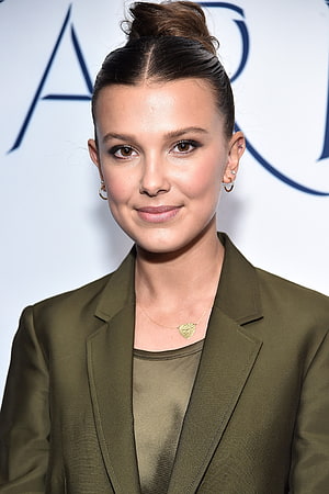 Millie Bobby Brown in olive blazer with heart pendant necklace and updo hairstyle HD phone wallpaper