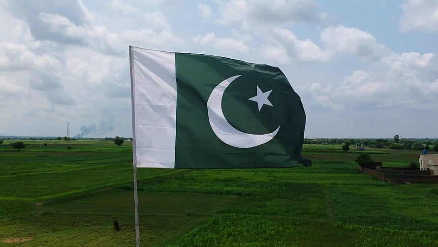 Pakistani National Flag Waving Over Lush Green Agricultural Fields Under a Cloudy Sky HD wallpaper