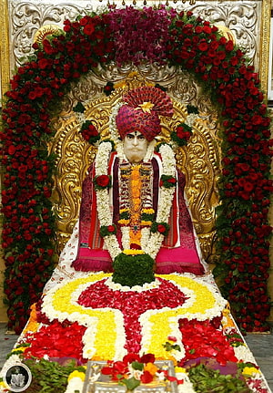 Shankar Maharaj adorned in vibrant floral garlands and traditional attire on a golden throne HD phone wallpaper