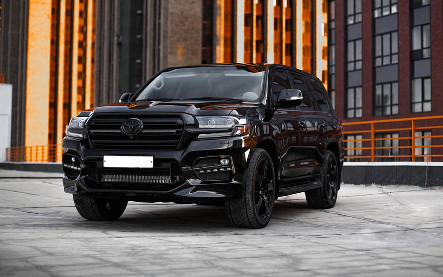 Black Toyota Land Cruiser 200 Series SUV Parked in Front of Modern Industrial Architecture HD wallpaper