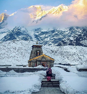Kedarnath Temple in Snow with Himalayan Peaks and a Pilgrim Walking Up the Steps HD phone wallpaper