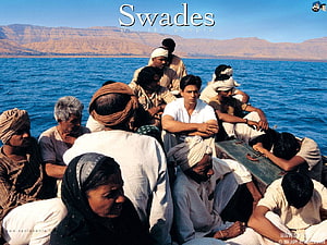 Swades Movie Scene: A Group of Men and Women Seated on a Boat in a Vast Blue Lake with Arid Mountains in the Background HD wallpaper