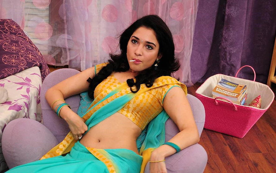Tamanna Bhatia in a yellow and teal saree reclining on a purple armchair HD wallpaper