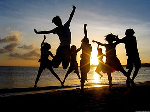 Silhouetted Friends Jumping Joyfully on Beach at Sunset HD wallpaper