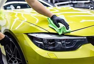 Professional Auto Detailing: Polishing a Vibrant Yellow Sports Car Hood with Microfiber Cloth HD wallpaper