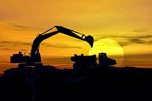 Heavy Excavator Silhouette Against Golden Sunset at Coal Mining Site HD wallpaper